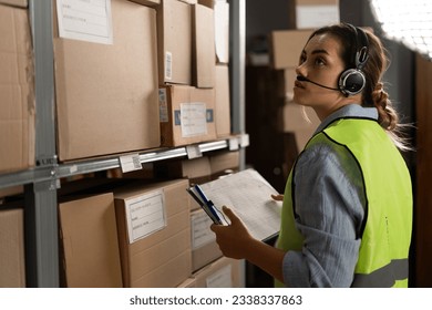 A warehouse worker checks the items against an inventory list on a clipboard. A logistics manager takes inventory using a warehouse management system in a distribution center. - Powered by Shutterstock