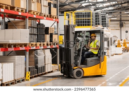 Warehouse worker driving forklift. Warehouse worker preparing products for shipmennt, delivery, checking stock in warehouse, order picking.