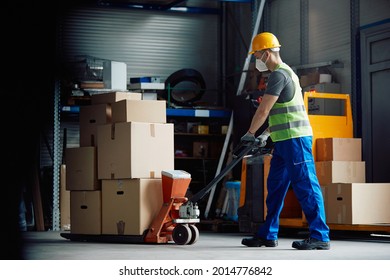 Warehouse worker with face mask pushing packages on pallet jack at storage compartment. - Powered by Shutterstock