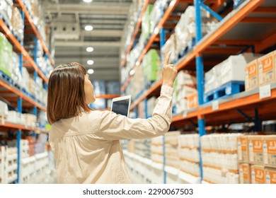 Warehouse worker hands holding tablet check stock on tall shelves in warehouse storage. Asian woman auditor or staff work looking up stock taking inventory in cargo store. Owner start up business. - Powered by Shutterstock