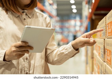 Warehouse worker hands holding tablet check stock on tall shelves in warehouse storage. Asian woman auditor or staff work looking up stock taking inventory in cargo store. Owner start up business. - Powered by Shutterstock