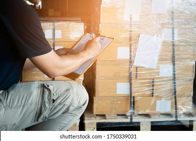 Warehouse worker holding clipboard writing on checklist for delivering shipment goods. Package boxes, Cargo shipment export, Industry warehouse shipping logistics and transport. - Shutterstock ID 1750339031