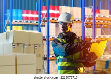 Warehouse Worker At Industrial Company. Male Storekeeper Next To Boxes. Warehouse Worker With Laptop In Hand. Warehouse Of Factory Or Plant. Man Working With Inventory Management Software. Art Focus