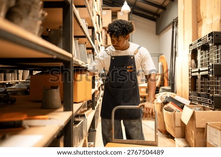 Warehouse worker lifting and moving boxes in a small business, representing logistics and manual handling