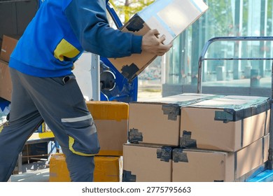 Warehouse worker loading cardboard parcels onto delivery truck