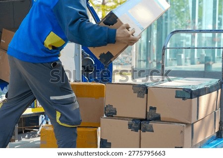 Warehouse worker loading cardboard parcels onto delivery truck