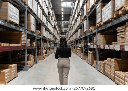 Warehouse worker navigating through spacious furniture warehouse with towering shelves stocked with cardboard boxes filled with flat-pack furniture