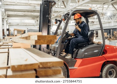 Warehouse worker operating a forklift while handling wooden materials.