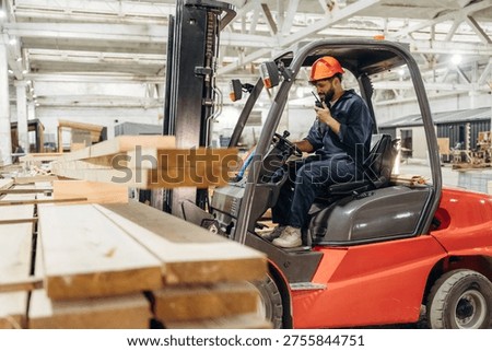Warehouse worker operating a forklift while handling wooden materials.