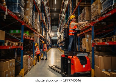 Warehouse worker reading bar codes on products while standing forklift - Shutterstock ID 1979740646