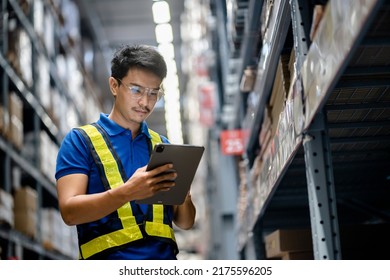 Warehouse Worker in safety suite using digital tablets to check the stock inventory in large warehouses, a Smart warehouse management system, supply chain and logistic network technology concept.