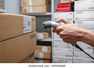 The warehouse worker scans the product bar code on the cardboard box using a hand held scanner before sending it to the customer