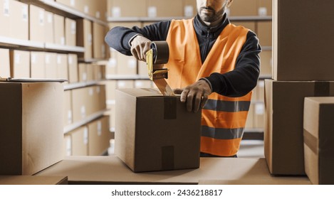 Warehouse worker sealing a cardboard box with adhesive tape, logistics and shipment concept - Powered by Shutterstock