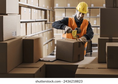 Warehouse worker sealing a cardboard box with adhesive tape, logistics and shipment concept - Powered by Shutterstock