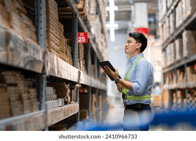 Warehouse worker in security uniform with tablet computer looking at merchandise in large warehouse Logistics and export business Logistics distribution center.
