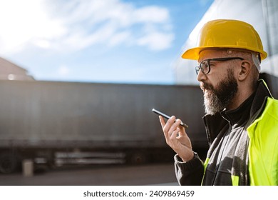 Warehouse worker standing outdoors, phone calling with truck driver. Warehouse receiver waiting for a delivery. - Powered by Shutterstock