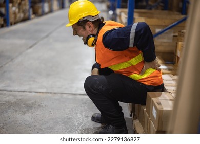 The warehouse worker suffered from a back injury while lifting and carrying heavy gear and keeping a twisted posture. Muscles can get strained, overused through continuous, repetitive movements. - Shutterstock ID 2279136827