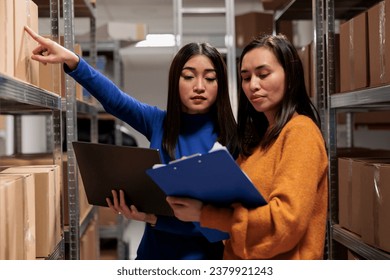 Warehouse worker and supply chain manager tracking inventory in storage room. Storehouse employees planning parcel stocking process optimization, analyzing orders checklist on clipboard - Powered by Shutterstock