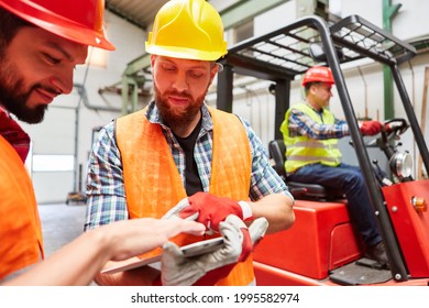 Warehouse Worker With Tablet PC Talks To Colleagues In The Shipping Company With Forklift Truck In The Background