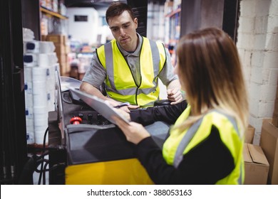 Warehouse Worker Talking With Forklift Driver In Warehouse