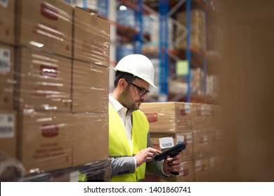 Warehouse worker using bar code scanner to organize goods distribution.