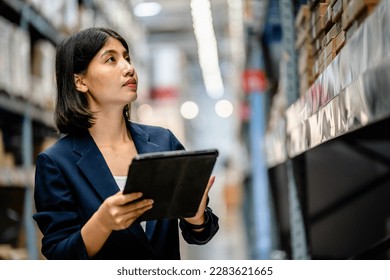 Warehouse Worker using smartphone and digital tablets to check the stock inventory in large warehouses, a Smart warehouse management system, supply chain and logistic network technology concept