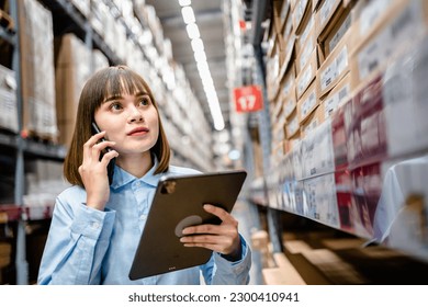 Warehouse Worker using smartphone and digital tablets to check the stock inventory in large warehouses, a Smart warehouse management system, supply chain and logistic network technology concept
