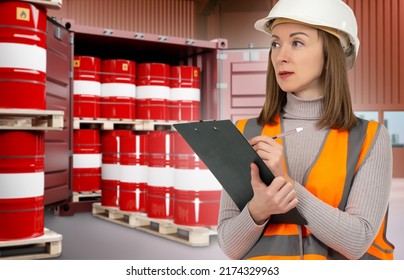 Warehouse Worker Woman. Warehouse Of Chemical Company. Girl In Orange Vest Is Holding Clipboard. Red Barrel Of Chemical Products. Chemistry Barrels In Blurred Maritime Container. Chemical Industry