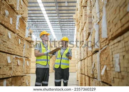 Warehouse worker working at lumber yard in Large Warehouse. Worker are  Inventory check at Storage shelves in lumberyard.
