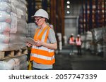 Warehouse worker working process checking the package using a tablet in a large warehouse distribution center. Caucasian female inspects cargo inventory.