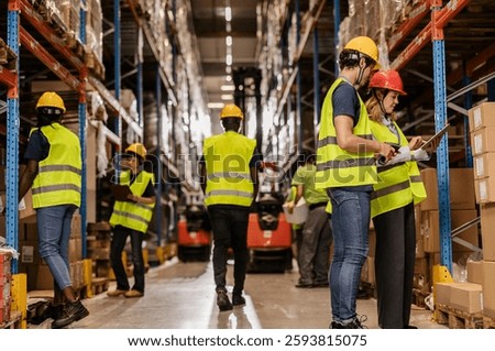 Warehouse workers are checking inventory and managing logistics using a digital tablet and barcode scanner, ensuring efficient operations in a busy distribution center