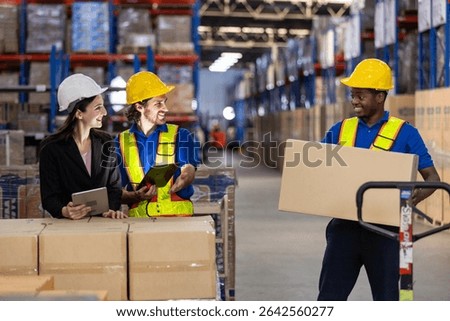 warehouse, workers are engaged in a discussion while employee prepares to lift a box. Active environment focused on logistics and teamwork.