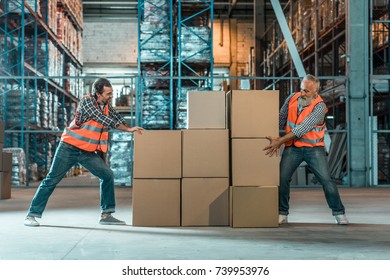 warehouse workers moving boxes while working together in storehouse 