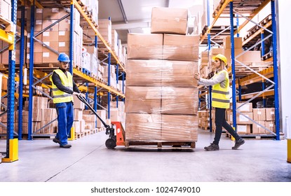 Warehouse Workers Pulling A Pallet Truck.
