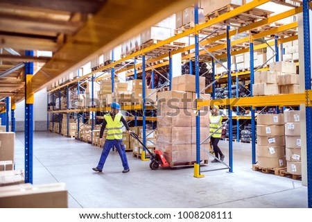 Warehouse workers pulling a pallet truck.