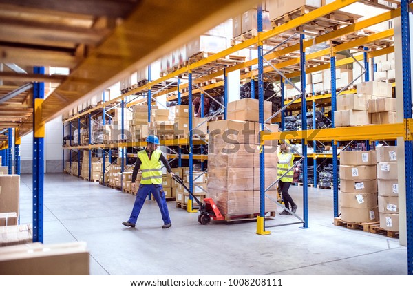 Warehouse workers pulling\
a pallet truck.