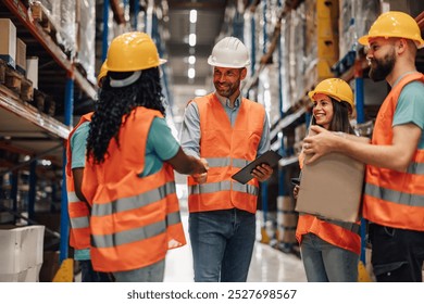 Warehouse workers in reflective vests and hard hats celebrate closing a deal, showcasing teamwork in logistics. Busy shelves highlight efficient supply chain partnership - Powered by Shutterstock