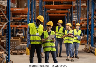 Warehouse workers in safety vests and hard hats using digital tablets and inventory management software to efficiently track and manage goods in the distribution center