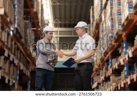 Warehouse workers shaking hands in storage facility, business agreement and partnership in logistics operation, inventory management collaboration, supply chain teamwork and professional deal concept.