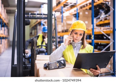 Warehouse Workers With Smartphone Working Together.