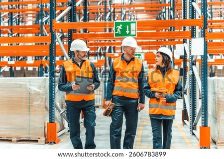 Warehouse workers walking through large distribution center, using barcode scanner and clipboard to check inventory