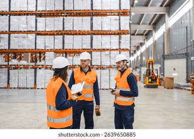 Warehouse workers wearing safety vests and helmets are using barcode scanners and clipboards to manage inventory and logistics in a large distribution center