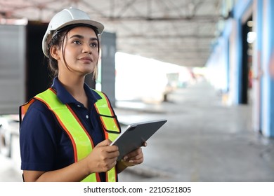 Warehouse Workers Woman With Hardhats And Reflective Jackets Using Tablet, Walkie Talkie Radio While Looking Away And Controlling Stock And Inventory In Retail Warehouse Logistics, Distribution Center