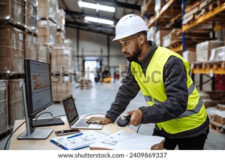 Warehouseman checking delivery, stock in warehouse on computer, pc. Warehouse manager using warehouse management software with scanner.