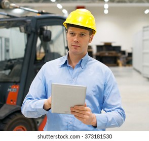 Warehouseman In Hard Hat With Tablet Pc At Warehouse.