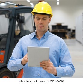 Warehouseman In Hard Hat With Tablet Pc At Warehouse.