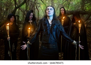 Warlocks in black cloaks spend a magical rite of the man in the woods.