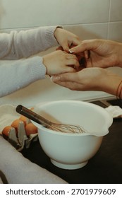 Warm and authentic maternity kitchen scene featuring a pregnant woman and her toddler daughter preparing a cake. Showing little girl’s flour-covered hands touching her mother’s baby bump.