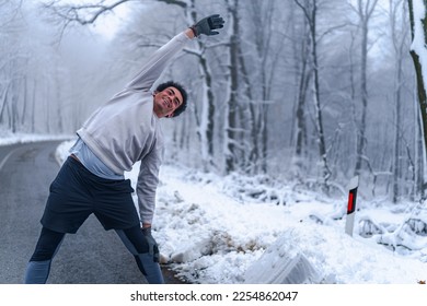 Warm up before going on a run in the foods on a snowy winter day, trees and ground are cover in snow - Shutterstock ID 2254862047