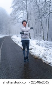 Warm up before going on a run in the foods on a snowy winter day, trees and ground are cover in snow - Shutterstock ID 2254862065